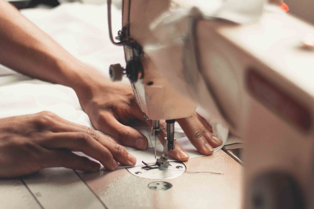 A woman sews fabric on an industrial sewing machine. The image shows just her hands.