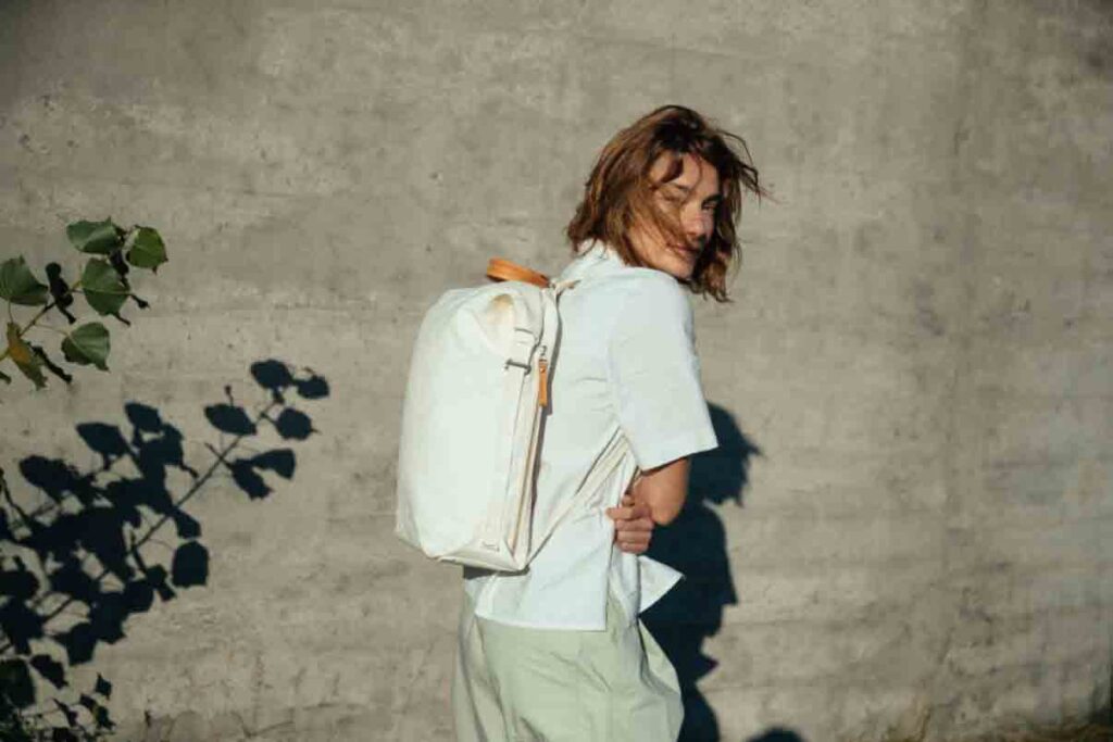 A woman wears a white Banantex backpack. She is turned away and hair covers her face.