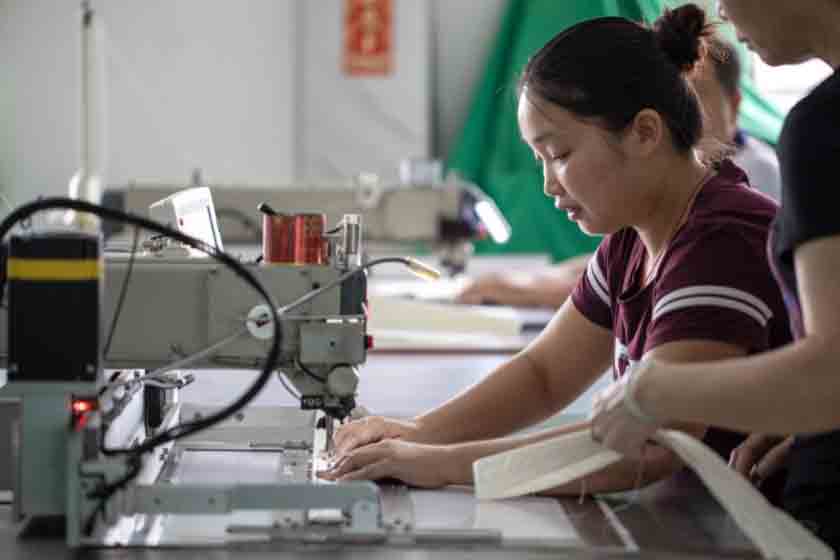 A woman sews a bananatex backpack in a studio