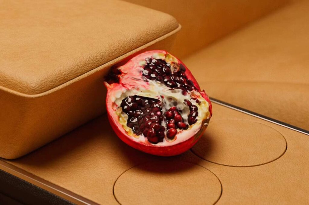 A pomegranate sits on a Polybion leather car console. The console is a neutral orange color.