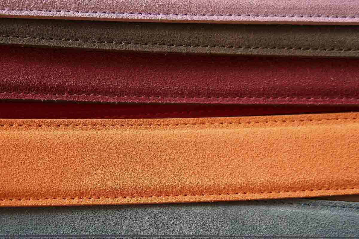 A stack of leather in different colors, including red, orange, gray, pinkn, red and brown.
