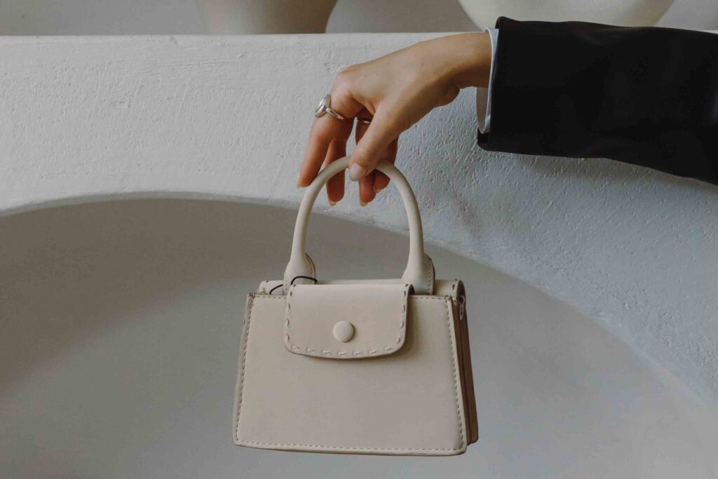 A woman holds a small white vegan leather purse.