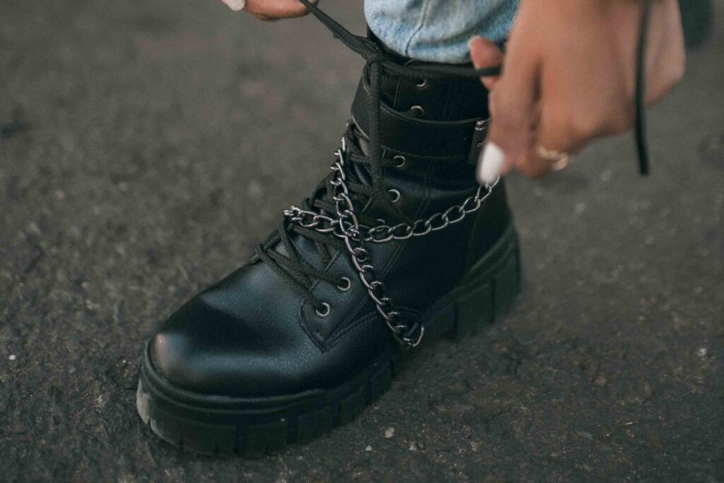 A woman ties a black leather boot.