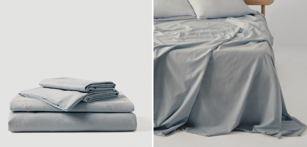 A slate gray set of sheets on a bed. to the left, they sit folded.