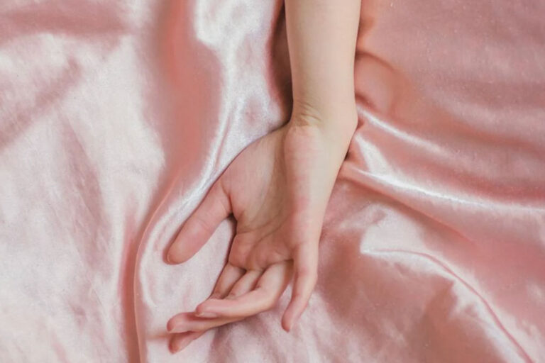 A woman's hand lays on top of pink mulberry silk